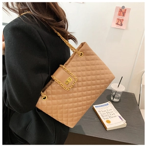Close-up of brown quilted tote bag featuring golden chain straps and turn-lock closure