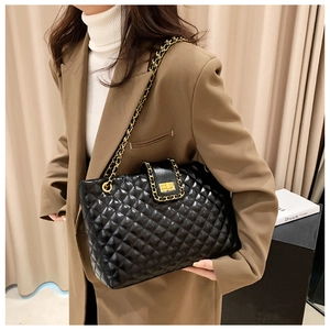 Close-up of black quilted tote bag featuring a gold twist lock and elegant chain strap