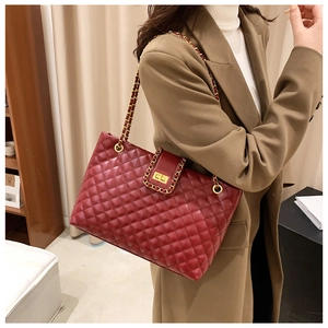 Macro detail of wine red quilted tote bag featuring golden chain strap and metal lock
