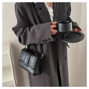 Close-up of black crocodile pattern crossbody bag with silver chain and top handle