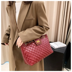 Detail of burgundy quilted tote bag featuring gold chain strap and metallic twist lock