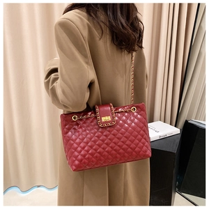 Detail of red quilted tote bag with golden chain strap and metallic twist lock closure