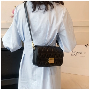 Close-up of quilted black crossbody bag with gold buckle on a model in blue dress