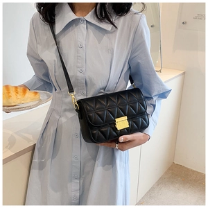 Close-up of black quilted leather crossbody bag with elegant gold metal square lock