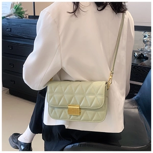 Detail of mint green crossbody bag featuring geometric quilted pattern and gold lock