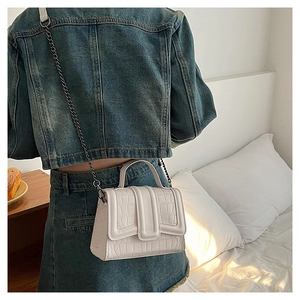 White faux crocodile skin handbag with silver chain strap worn by a model in casual denim