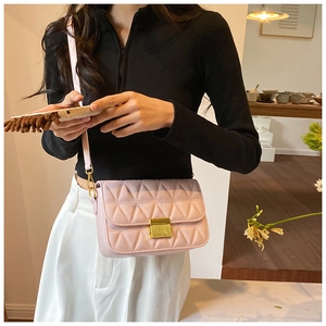 Detailed close-up of light pink quilted crossbody bag with gold buckle and adjustable strap