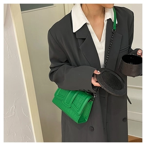 Detail of bright green faux crocodile leather handbag with metal chain and buckle strap