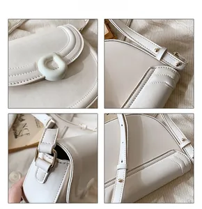 Detailed close-up showing white leather texture, golden buckle, and stitching of the saddle bag