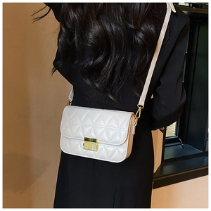 Detailed back view of a beige quilted crossbody bag with golden clasp on a black outfit