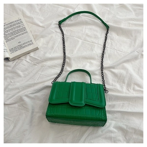Detail of green faux crocodile skin texture on a stylish cross-body handbag
