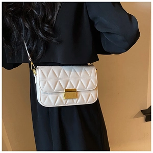 Detail of white quilted handbag with elegant gold rectangular lock and metal chain strap