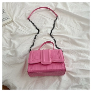 Detailed view of pink croc-embossed leather texture with metal chain and top handle