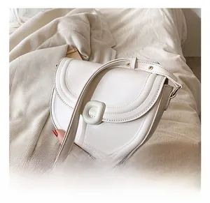 Close-up of white leather saddle bag showing round buckle and gold hardware detail