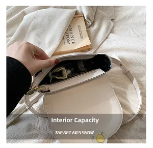 Internal capacity of beige leather saddle bag showing gold hardware and dark fabric lining