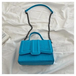 Macro view of electric blue crocodile texture handbag with metal chain strap detail