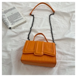 Close-up of orange faux leather handbag with crocodile pattern and metal chain strap