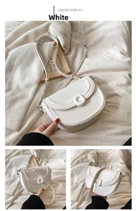 Detail view of white glossy leather saddle bag featuring a round buckle and retro props