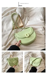 Detail of light green faux leather saddle bag with adjustable strap on beige background