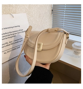 Detail of minimalist cream saddle bag with adjustable strap and decorative buckle