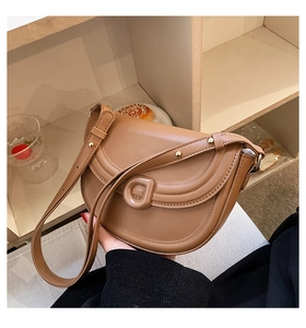 Close-up of dark brown saddle bag with gold rivets and unique U-shaped buckle detail