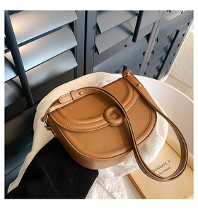 Detail view of brown leather saddle bag on white fabric with blue background