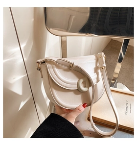 Detail of beige saddle bag featuring a stylish D-buckle and smooth faux leather texture