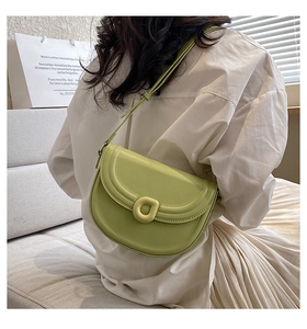 Back view of light green leather saddle bag worn by model in a cozy indoor setting