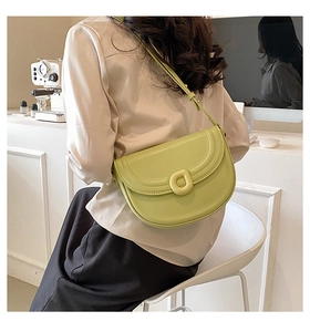 Close-up of avocado green leather saddle bag with D-shaped buckle worn by a model