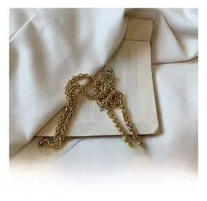 Detail of golden metal chain strap on a pink quilted crossbody bag with textured hardware