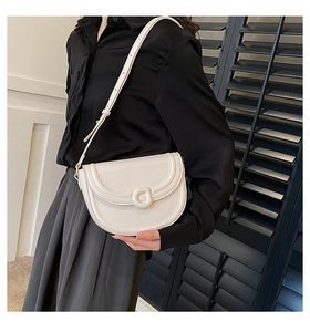 Detail of minimalist cream saddle bag with adjustable shoulder strap and ring buckle