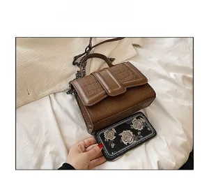 Borsa a tracolla marrone motivo coccodrillo con confronto dimensioni smartphone