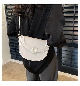 Detail view of a cream half-moon saddle bag styled on model with black shutter background