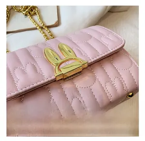 Close-up of pink quilted leather bag with a decorative golden rabbit metal clasp