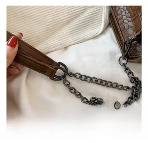 Dettaglio borsa marrone in pelle coccodrillo con catena in metallo grigio scuro