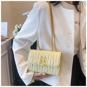 Detail of cream quilted bag with rabbit clasp and elegant gold chain strap