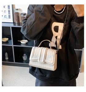 Detail of cream white croc-embossed square bag with chain strap and handle