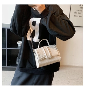 White crocodile pattern crossbody bag with silver chain strap shown as a shoulder bag