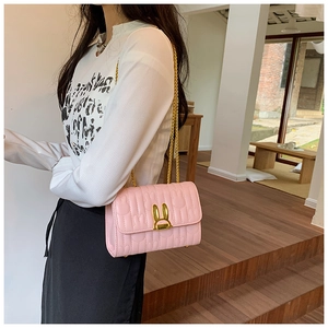 Pink quilted shoulder bag with gold rabbit ear clasp and chain strap on a model