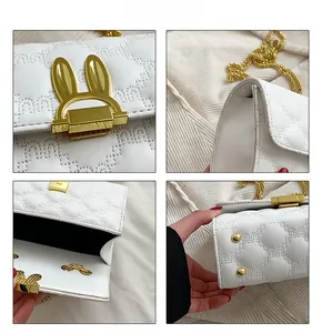 Detail view of white quilted shoulder bag with golden rabbit lock and chain strap