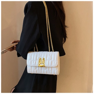 Detail of white quilted crossbody bag with golden bunny-ear lock and chain strap