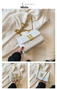 Detail of white quilted crossbody bag with golden rabbit buckle and metal chain strap