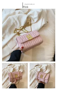 Detail view of a pink quilted crossbody bag featuring a golden bunny ear twist lock