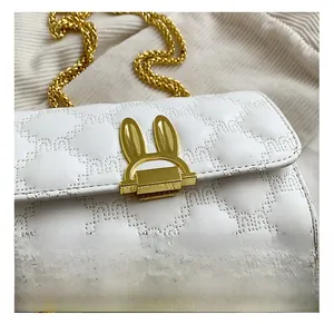 Close-up of golden rabbit-shaped metal lock on white quilted leather shoulder bag