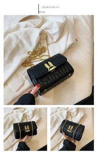 Detail of black quilted crossbody bag with gold rabbit ear lock and chain strap on white coat