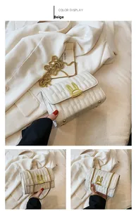 Detail of beige quilted square bag with gold rabbit ear clasp and metal chain strap