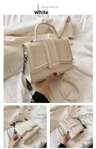 Detail view of white crocodile pattern crossbody bag with metallic chain and top handle