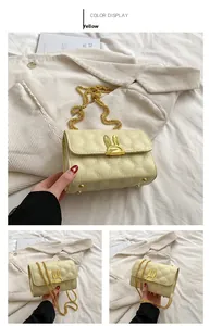 Detail of yellow quilted bag featuring golden rabbit clasp and chain shoulder strap