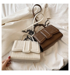 Detail showing crocodile texture and metal chain on beige and brown flap bags