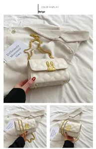 Close-up of beige quilted crossbody bag with rabbit ear gold buckle and chain strap